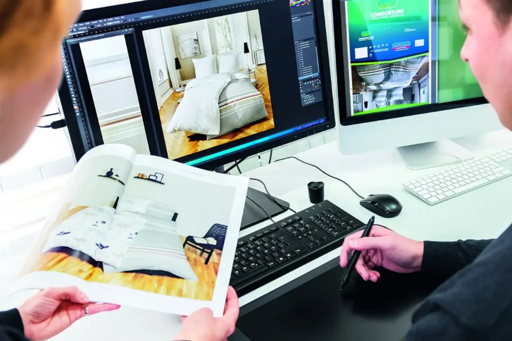 Foto von einem Computer-Monitor und Menschen bei der Arbeit